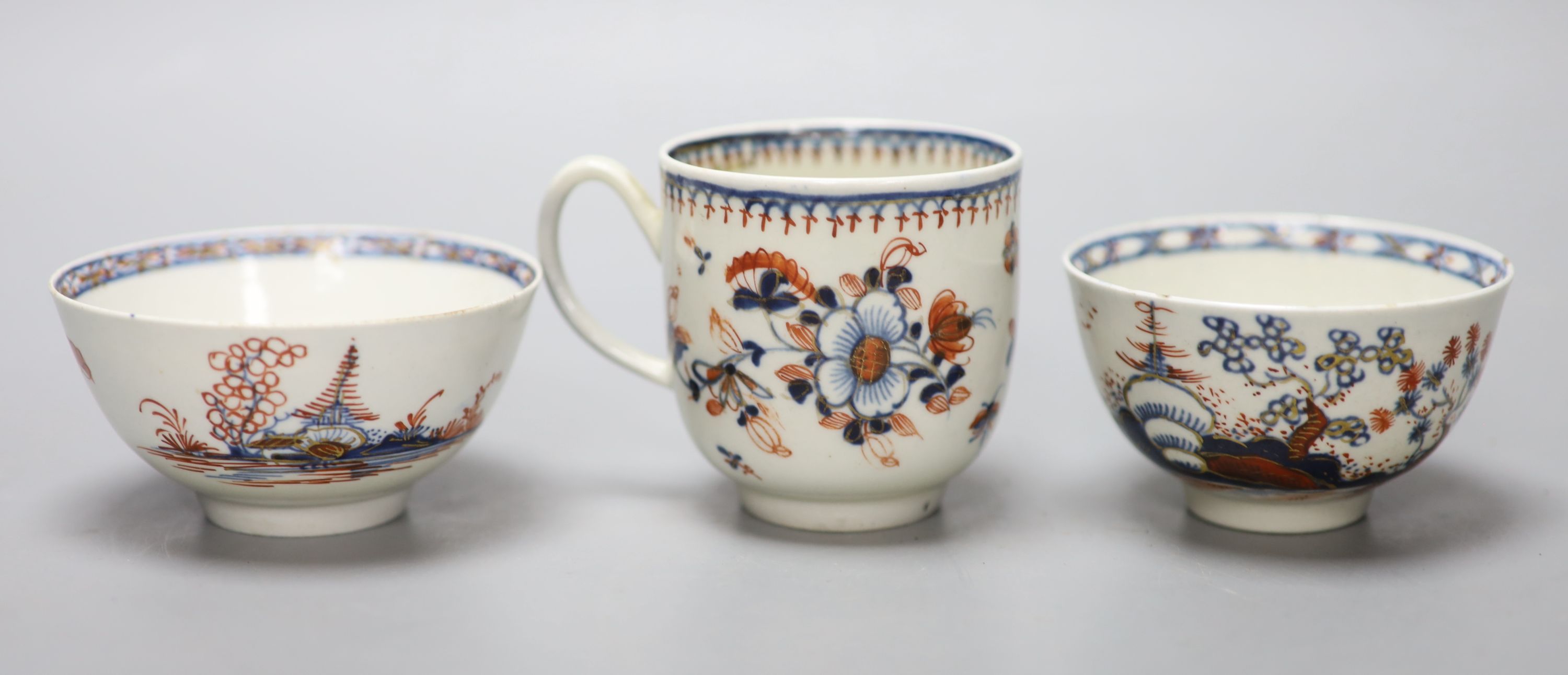 An 18th century Liverpool coffee cup and two teabowls, painted in blue with overglaze red highlights